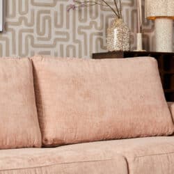 Mokana meubelen roze slaapbank met kussens in een modern interieur met decoratieve muur en accessoires.
