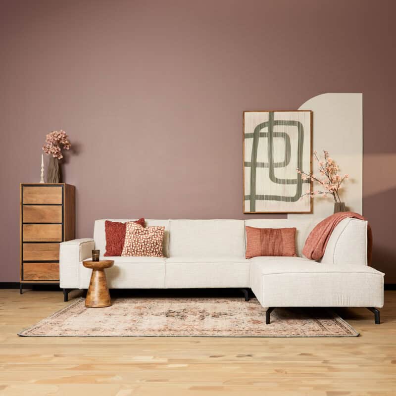 Moderne woonkamer met Mokana bank, decoratieve kussens, houten kast en kunstwerk op muur in een stijlvolle, gezellige ruimte.