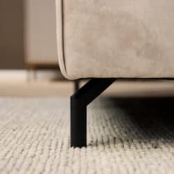 Close-up van een beige lounge fauteuil met zwarte metalen poot, perfect voor moderne woonkamers.