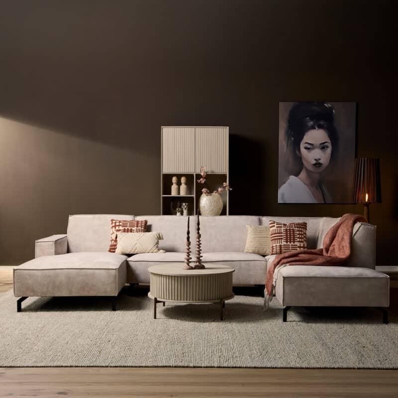 Moderne woonkamer met grote L-vormige bank, decoratieve kussens, kunstwerk en sfeerverlichting, perfect voor stijlvolle interieurs.