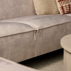 Dichtbijzicht van een lichte grijze lounge bank met een scheur in de bekleding, geschikt voor modern interieur.